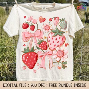 May include: Cream-colored t-shirt featuring a whimsical strawberry design. The graphic includes pink bows, flowers, and red strawberries with green leaves. The text at the bottom reads "DIGITAL FILE : 300 DPI : FREE BUNDLE INSIDE."