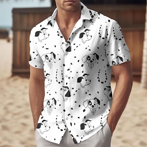 May include: White short-sleeved shirt featuring a repeating pattern of black and white Dalmatian dog faces and spots. The shirt has a classic collar and is unbuttoned at the top.