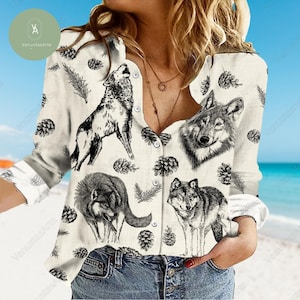 Puede incluir: Una camisa blanca de botones con manga larga con un patrón repetido de ilustraciones de lobos en blanco y negro y piñas.