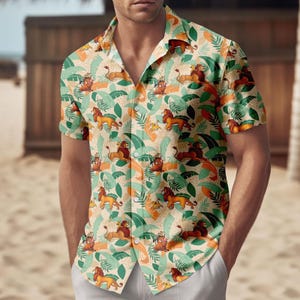 Può includere: Camicia a maniche corte con bottoni con un motivo ripetuto di leoni, foglie tropicali e altri personaggi. La camicia presenta uno sfondo beige con accenti arancioni, verdi e marroni. La camicia ha un colletto classico.