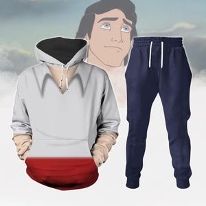 Puede incluir: Una sudadera blanca y roja con capucha negra y un pantalón de chándal azul marino. La sudadera tiene cuello en V y cordón de ajuste. El pantalón de chándal tiene cordón de ajuste y rayas blancas a los lados.