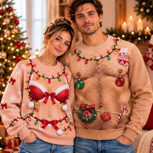 May include: Two beige long-sleeve jumpers featuring realistic skin-tone prints. One jumper displays a red lace bra design with Christmas lights and bows. The other jumper features a hairy chest print with ornaments, a wreath, and a candy cane.