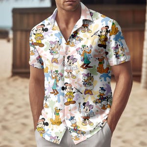 May include: White button-down shirt featuring a colorful pattern of cartoon characters, including Mickey Mouse, Minnie Mouse, Donald Duck, and Goofy, with paint splatters. The short-sleeved shirt has a classic collar and is made of a lightweight fabric.