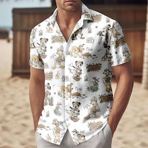 May include: White button-down shirt featuring a repeating pattern of cartoon characters, including Mickey Mouse, Donald Duck, and Pluto, in safari attire. The shirt has short sleeves and a camp collar, with the words "Animal Kingdom Expedition" on the design.