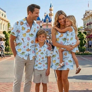 May include: A family of four wearing matching light blue shirts and dresses with a colorful sea creature pattern. The shirts have short sleeves, and the dresses are sleeveless. The family is smiling in front of a castle.