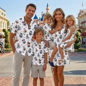 May include: A family of five wearing matching white shirts and dresses with a colorful cartoon character pattern. The shirts have short sleeves and the dresses are sleeveless. The family is smiling in front of a castle.