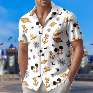 May include: White short-sleeved shirt with a Halloween pattern. The design features orange anchors, Mickey Mouse life preservers, spiderwebs, bats, and other Halloween graphics. The shirt is worn by a person.