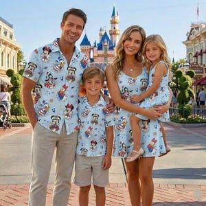 May include: A family of four in matching light blue outfits patterned with cartoon characters. The outfits include a button-down shirt, a sleeveless dress, and shorts. A castle and street are visible in the background.