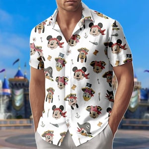 Puede incluir: Camisa blanca de manga corta con un estampado repetido de personajes de dibujos animados de piratas, incluyendo Mickey Mouse, Minnie Mouse, Donald Duck y Pluto. Los personajes llevan sombreros de pirata y pañuelos. Otros elementos temáticos de piratas incluyen llaves, anclas y mapas del tesoro.