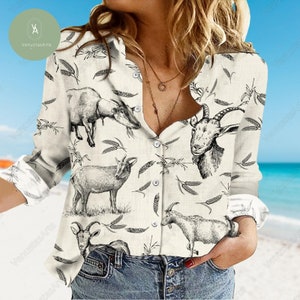 Könnte beinhalten: Ein weißes Hemd mit Knöpfen und einem schwarz-weißen Ziegenmuster. Das Hemd hat eine lockere Passform und lange Ärmel.