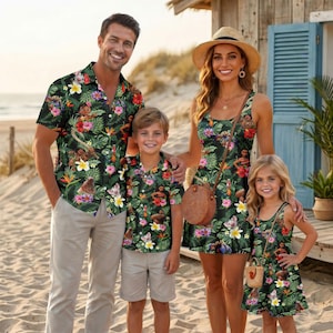 May include: A family wearing matching outfits with a dark green tropical print featuring hibiscus flowers and Moana characters. The set includes a short-sleeved button-down shirt, a sleeveless dress, and a child's shirt and dress with the same pattern.