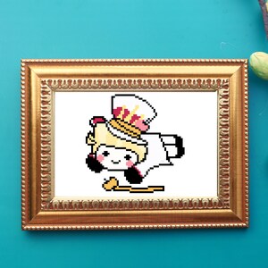 Op de afbeelding: Een gepixelde illustratie van een stripfiguur in een gouden lijst. Het personage draagt een witte outfit, een hoge hoed met roze en gouden accenten en houdt een gouden scepter vast. De achtergrond is wit.