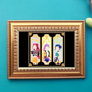 May include: A framed pixel art print featuring three stylized figures in a gold frame. Each figure is set against a colorful background. The frame is gold and the background is a teal color.