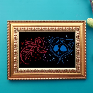 May include: A gold-framed cross-stitch artwork. The image shows two cartoon figures, one red and one blue, on a black background with stars. The frame is gold, and the background is teal.