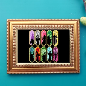 May include: A framed cross-stitch artwork featuring colorful silhouettes of Disney villains against a black background. The gold frame surrounds the artwork, which is displayed on a teal wall. The artwork showcases a variety of characters in a pixelated style.