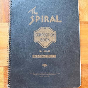 May include: A dark blue spiral-bound composition book with gold lettering and design. The cover reads "The Spiral Composition Book" and "Marginal Rule". The notebook is a No. 891-M.