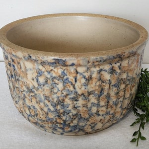May include: A white ceramic bowl with a blue and brown mottled glaze. The bowl has a fluted design around the rim.