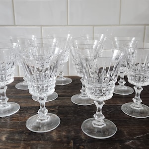 May include: Set of eight clear glass wine glasses with a cut crystal design. The glasses have a wide bowl and a tall stem.