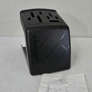 May include: Black knife block with slots for various knives. The block features a geometric pattern and the brand name "perware". A white paper with the text "U-Series Knife Block" is visible in the foreground. A kitchen storage item.
