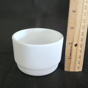 May include: A white ceramic planter with a double rim. The planter is approximately 2.5 inches tall and 3 inches in diameter.