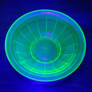 May include: A green glass bowl with a fluted design. The bowl is made of uranium glass and glows under a black light.