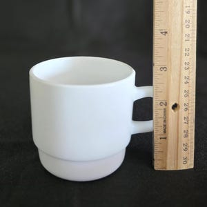 May include: A white ceramic mug with two handles. The mug is stacked in two sections and is approximately 3 inches tall.