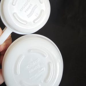 May include: Two white ceramic bowls with a raised rim and a smooth, glossy finish. The bottom of each bowl has the text "Arcopal France" and a logo with a crown.