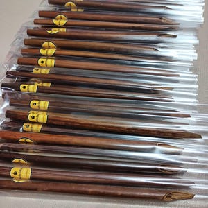 May include: A bundle of brown wooden calligraphy pens wrapped in clear plastic. The pens have a pointed tip and a label that reads "Elegant Calligraphy".