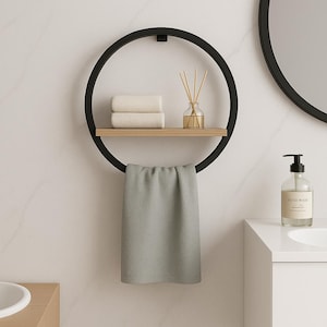 May include: A black metal circular towel rack with a wooden shelf holding two folded towels and a glass diffuser. A gray towel hangs below. A round mirror and a soap dispenser are visible in the background.