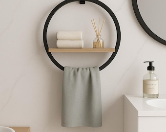 May include: A black metal circular towel rack with a wooden shelf holding two folded towels and a glass diffuser. A gray towel hangs below. A round mirror and a soap dispenser are visible in the background.