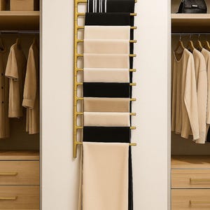 May include: A gold scarf rack on a white wall, holding scarves in black, beige, and white. The rack is between two wooden wardrobes. The scarves are neatly arranged, creating a stylish display.