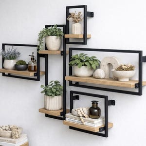May include: A modern wall shelf unit with a black metal frame and natural wood shelves. The shelves display potted plants, decorative bowls, and other home decor items. The unit is mounted on a white wall, creating a stylish display.
