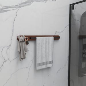 May include: A wooden towel rack with a gray towel, a gray hooded towel, and a small brush. The rack is mounted on a white marble wall. The hooded towel has an elephant design.