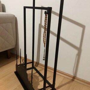 May include: Black metal stand with a silhouette of a mosque and a crescent moon. A wooden prayer bead necklace hangs from the top of the stand.