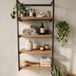 May include: A black metal and wood shelf unit filled with bathroom accessories. The shelves hold rolled towels, candles, plants, and bottles of lotions and soaps. The unit is mounted on a light gray wall.