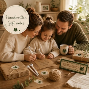 A family of three, a mother, father, and daughter, are sitting together at a table, with the daughter writing in a notebook. The table is decorated with various items, including a sign that reads "Feline Fancy" and a mug with a cat design.
