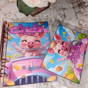 May include: Clear binder with rose gold hardware and two inserts featuring a cartoon pig driving a pink car. The inserts have the text "Pink Pig Saver" and "The Buy Ly". The pig is wearing a necklace and surrounded by gold coins.