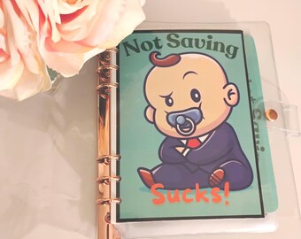 May include: A clear plastic binder with a gold metal ring mechanism. The binder has a green and white insert with a cartoon baby wearing a suit and a dummy. The text on the insert reads "Not Saving Sucks!"