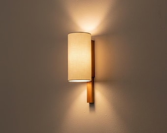 Modern design cylindrical wall light handmade with oak wood and natural linen fabric.