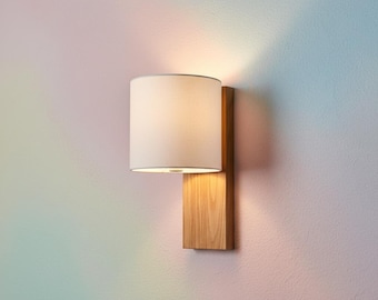 Wall light with a natural white linen shade and solid oak frame, with plug-in option. Elegant design.