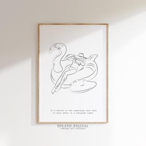 Op de afbeelding: Een ingelijste kunstdruk met een minimalistische lijntekening van een persoon op een flamingo-zwemband. Het kunstwerk bevat de tekst: "Het is beter om iets één keer te zien dan er duizend keer over te horen."