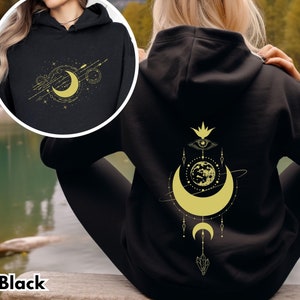 May include: Black hoodie with a gold moon and stars design on the front and a gold moon, eye, and flower design on the back.