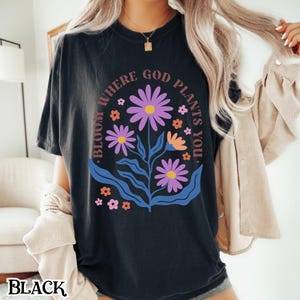 May include: Black t-shirt with a floral design and the text "Bloom Where God Plants You."