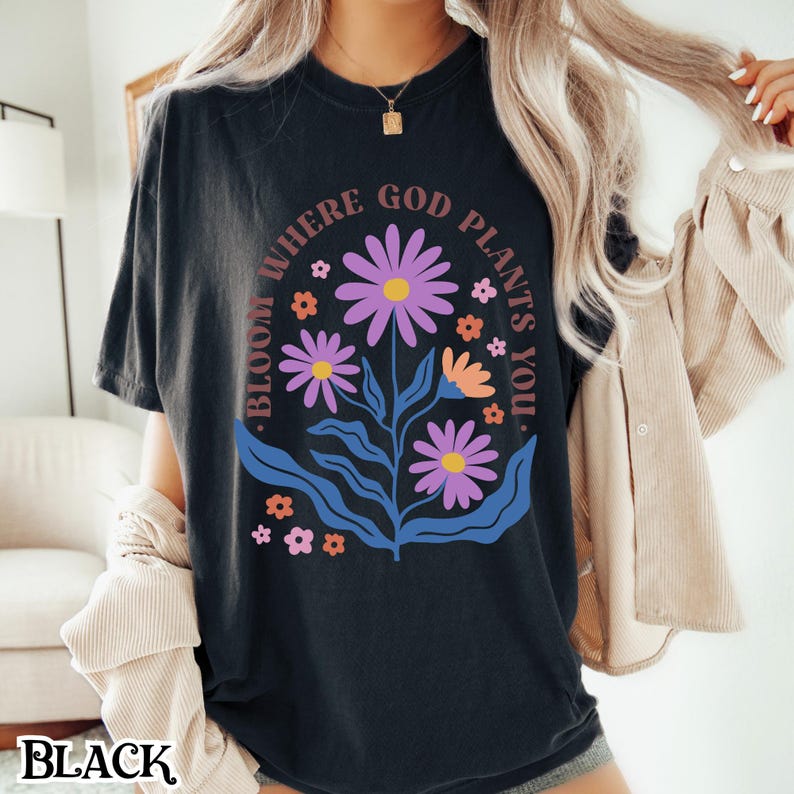 May include: Black t-shirt with a floral design and the text "Bloom Where God Plants You."