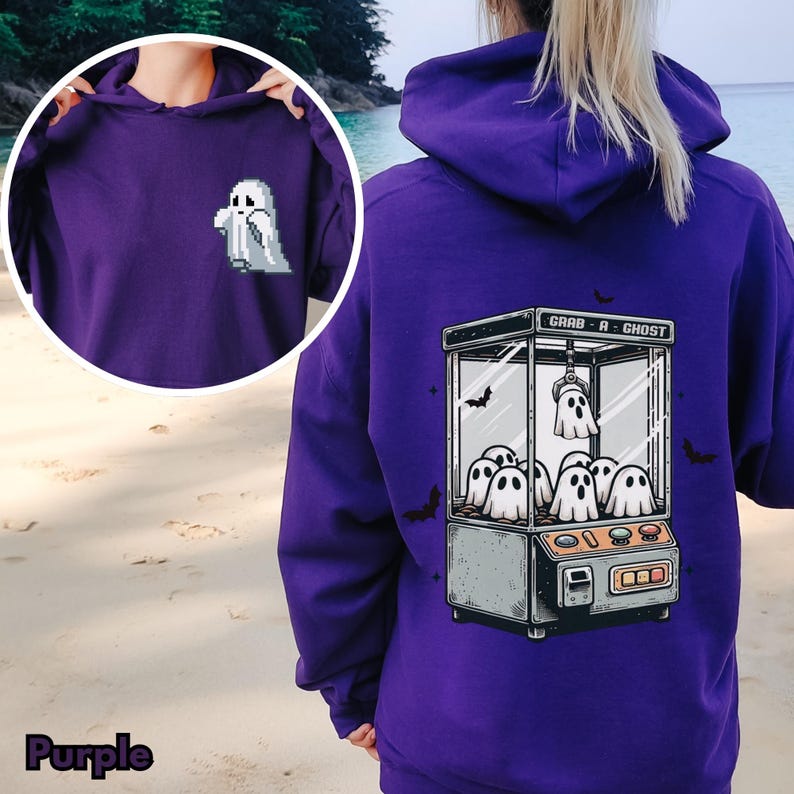 Pode incluir: Moletom roxo com capuz com um gr&aacute;fico de uma m&aacute;quina de garra fantasma nas costas e um &uacute;nico fantasma na frente. O texto na m&aacute;quina de garra diz "Grab-A-Ghost".