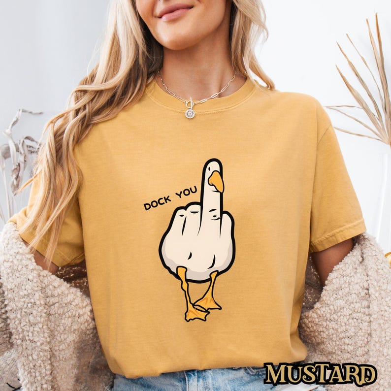 May include: A yellow t-shirt with a cartoon goose giving the middle finger. The goose is white with a yellow beak and feet. The text "Duck You" is printed on the shirt.