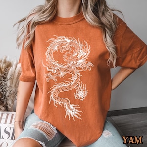 May include: A rust-colored t-shirt with a white graphic of a dragon.