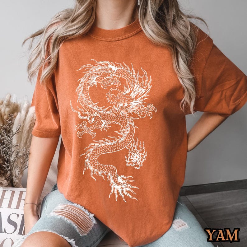 May include: A rust-colored t-shirt with a white graphic of a dragon.
