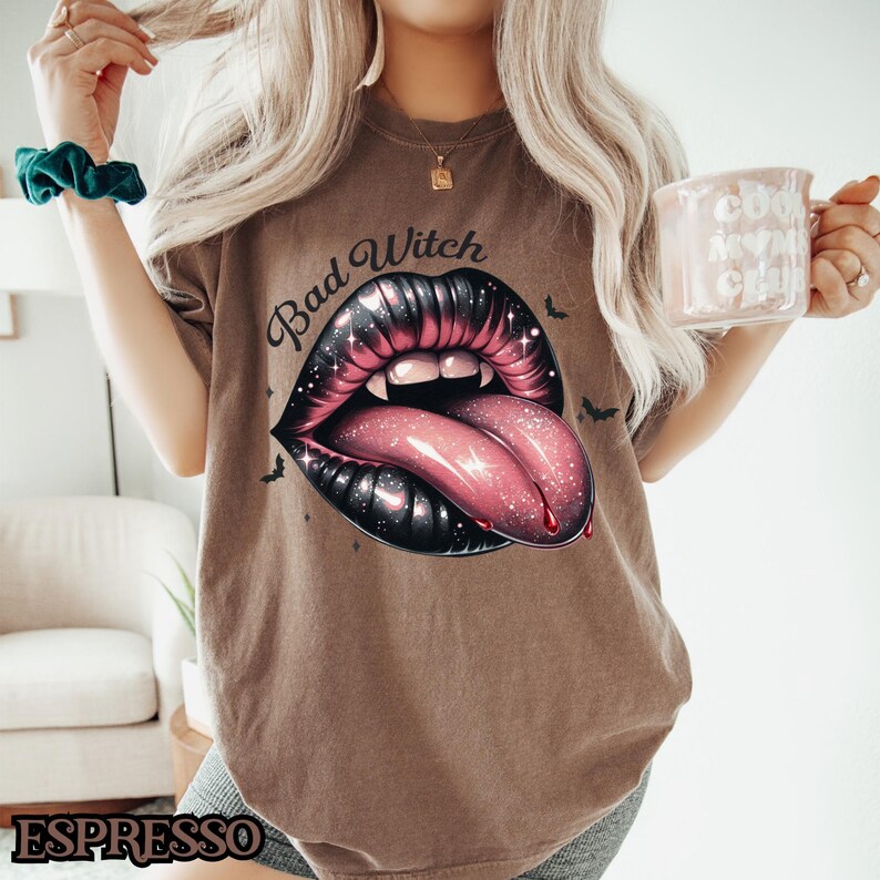 Peut inclure: Un t-shirt marron avec un graphique d'une bouche noire et rouge avec une langue qui sort. Le texte "Bad Witch" est imprim&eacute; au-dessus de la bouche.