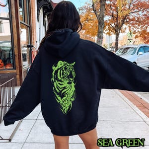 May include: Black hoodie with a green tiger graphic on the back. The text "SEA GREEN" is printed on the bottom of the image.